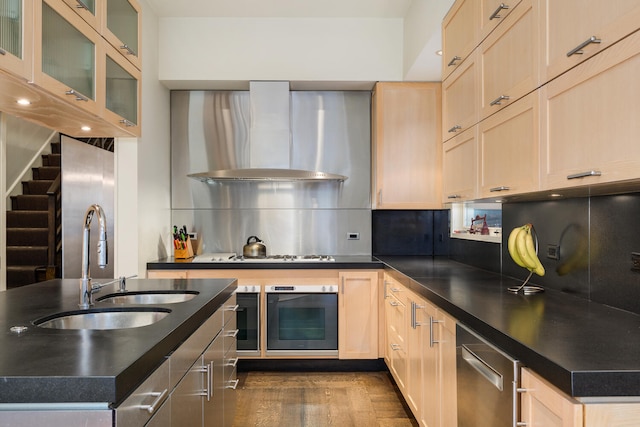 kitchen featuring sink, wall chimney exhaust hood, tasteful backsplash, oven, and light brown cabinetry