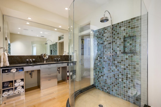 bathroom with backsplash, vanity, wood-type flooring, and tiled shower