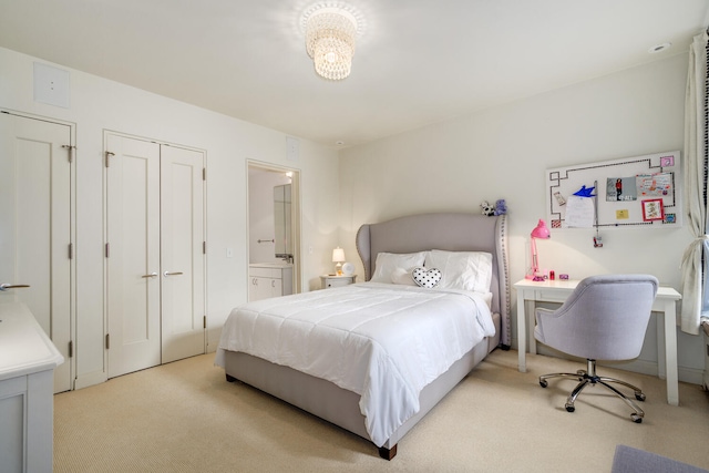 bedroom featuring ensuite bath, light carpet, and two closets