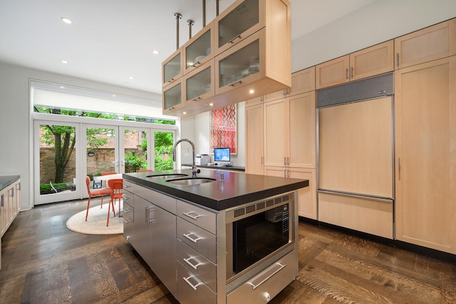 kitchen with french doors, a center island with sink, sink, built in appliances, and dark hardwood / wood-style floors