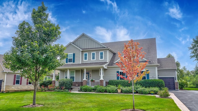 craftsman inspired home with a porch, a garage, and a front lawn