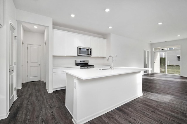 kitchen featuring dark wood-type flooring, white cabinets, sink, an island with sink, and stainless steel appliances