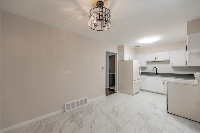 kitchen featuring white fridge, white cabinetry, hanging light fixtures, and sink