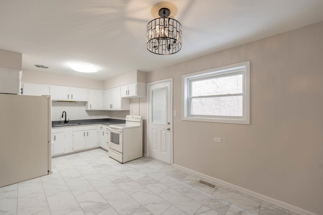 kitchen with white appliances, decorative light fixtures, and white cabinetry