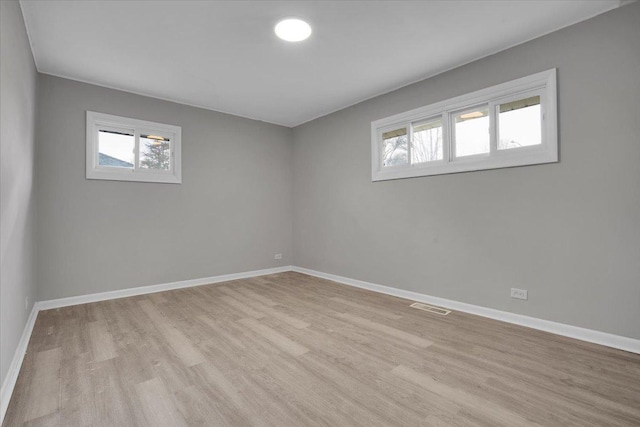 empty room with plenty of natural light and light hardwood / wood-style flooring