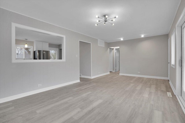 unfurnished living room featuring a chandelier and light hardwood / wood-style floors