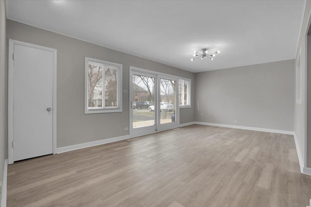 empty room featuring light hardwood / wood-style floors and a notable chandelier