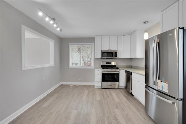 kitchen featuring pendant lighting, light hardwood / wood-style floors, white cabinets, and appliances with stainless steel finishes