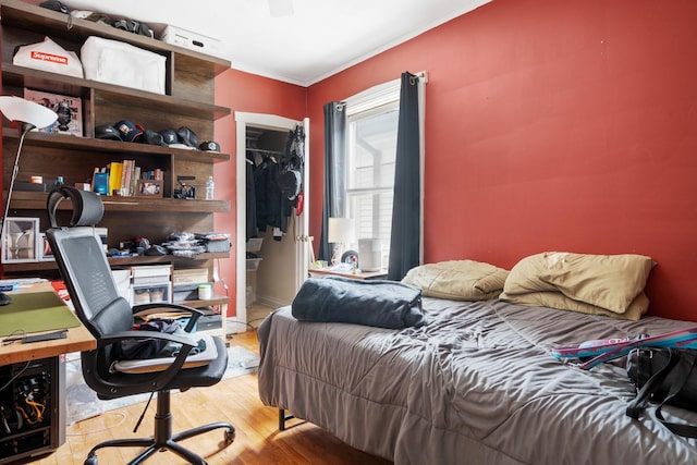 bedroom featuring a closet, light hardwood / wood-style floors, and ornamental molding