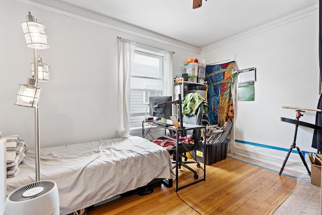 bedroom with hardwood / wood-style flooring, ceiling fan, and crown molding