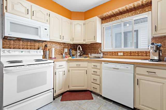 kitchen featuring decorative backsplash, light tile patterned flooring, and white appliances