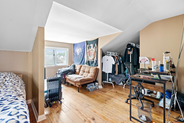 bedroom with radiator, wood-type flooring, and vaulted ceiling