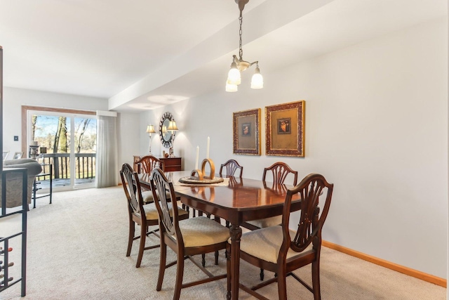 dining space with light colored carpet and a notable chandelier