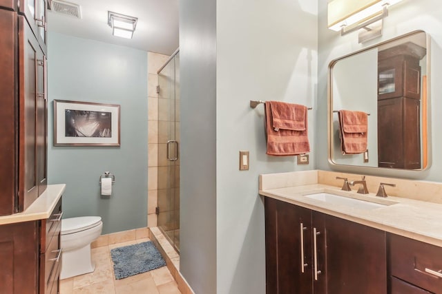 bathroom with tile patterned floors, vanity, a shower with shower door, and toilet