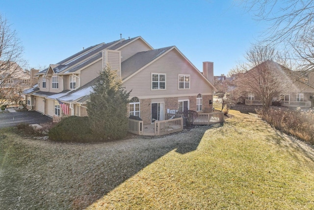 rear view of property with a lawn, a garage, and a deck