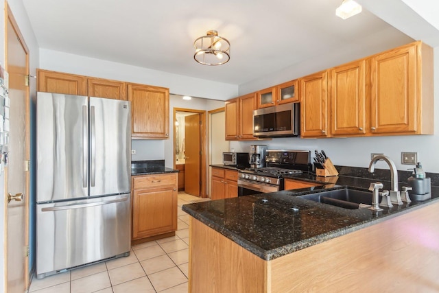 kitchen featuring sink, kitchen peninsula, dark stone counters, light tile patterned flooring, and appliances with stainless steel finishes