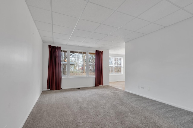 empty room featuring light carpet and a paneled ceiling