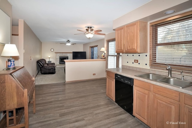 kitchen featuring sink, ceiling fan, a fireplace, black dishwasher, and tasteful backsplash