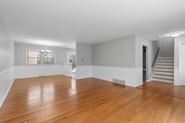 empty room with a notable chandelier and light hardwood / wood-style flooring