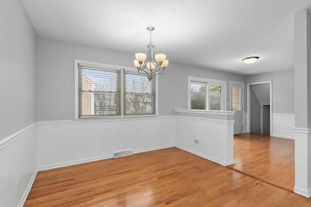 unfurnished dining area featuring light hardwood / wood-style flooring and a notable chandelier