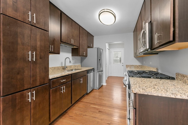 kitchen featuring light wood-type flooring, stainless steel appliances, dark brown cabinetry, and sink