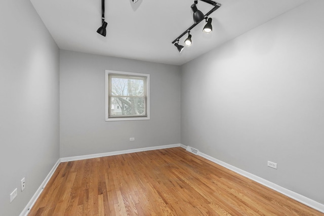 empty room featuring track lighting and light wood-type flooring