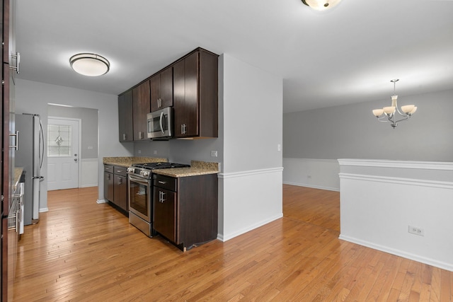 kitchen featuring pendant lighting, dark brown cabinetry, light wood-type flooring, and stainless steel appliances