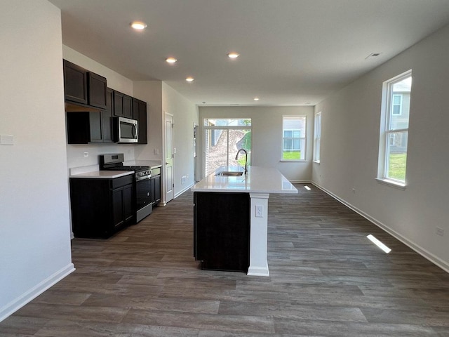 kitchen with dark hardwood / wood-style flooring, sink, stainless steel appliances, and an island with sink