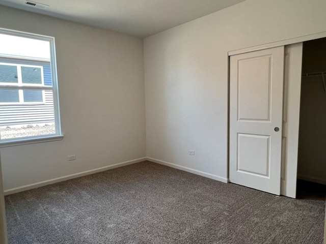 unfurnished bedroom with dark colored carpet and a closet