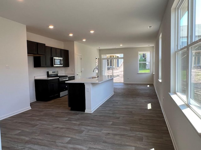 kitchen featuring stainless steel appliances, dark hardwood / wood-style floors, a center island with sink, and sink