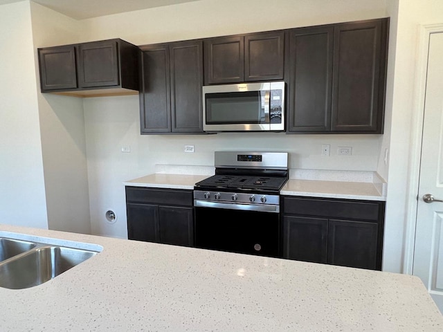 kitchen with appliances with stainless steel finishes, dark brown cabinets, and sink