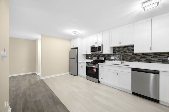 kitchen with decorative backsplash, stainless steel appliances, sink, light hardwood / wood-style flooring, and white cabinets