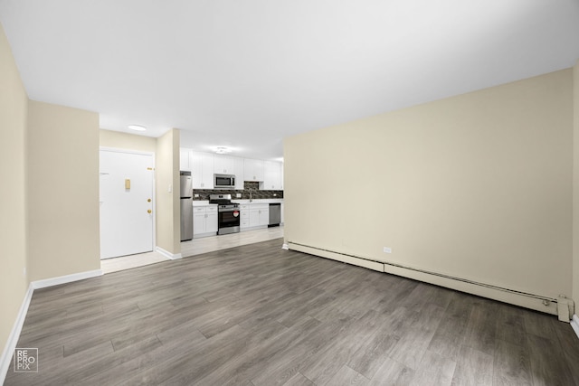 unfurnished living room featuring baseboard heating and light wood-type flooring