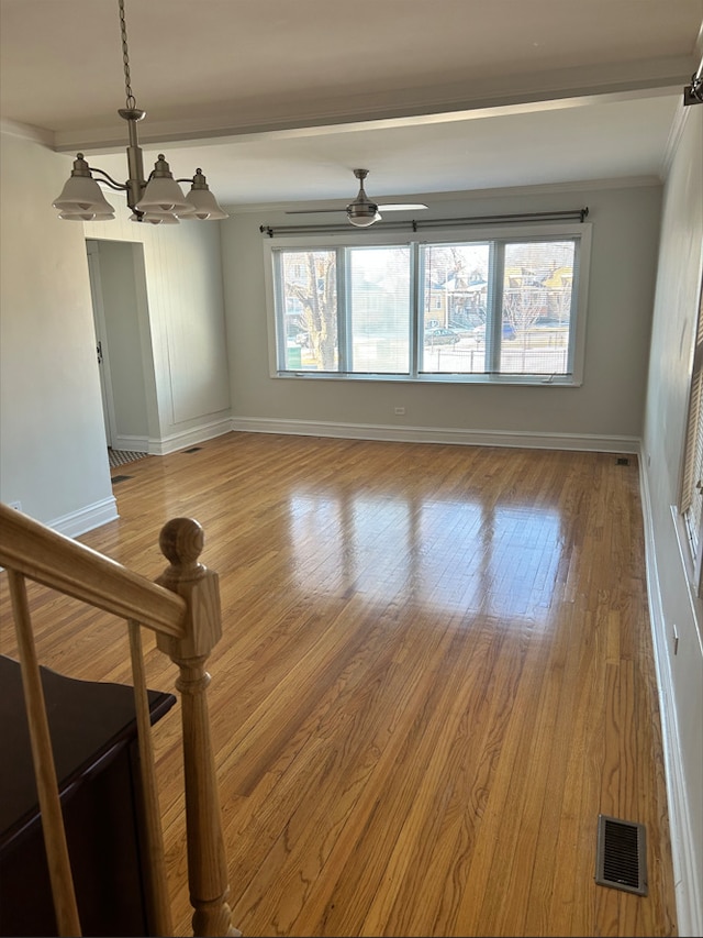 empty room featuring wood-type flooring, ceiling fan with notable chandelier, and crown molding