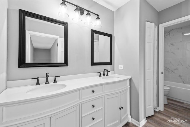 full bathroom with hardwood / wood-style floors, vanity, toilet, and tiled shower / bath