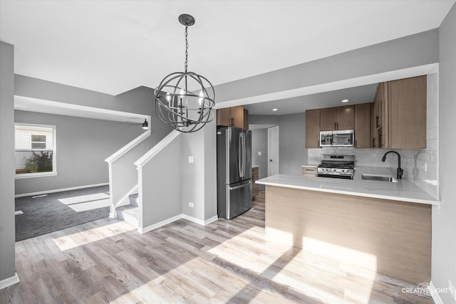 kitchen with sink, kitchen peninsula, pendant lighting, decorative backsplash, and appliances with stainless steel finishes