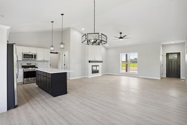 kitchen with appliances with stainless steel finishes, a kitchen island, ceiling fan, decorative light fixtures, and white cabinetry