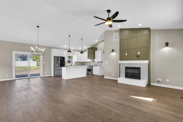 unfurnished living room featuring high vaulted ceiling, a premium fireplace, dark hardwood / wood-style flooring, and ceiling fan with notable chandelier