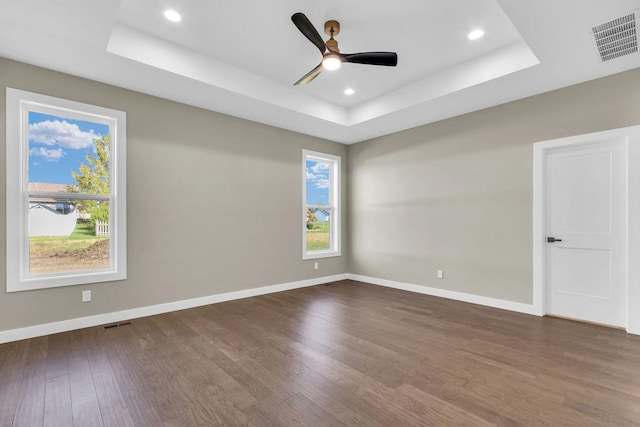 unfurnished room featuring ceiling fan, dark hardwood / wood-style flooring, and a tray ceiling