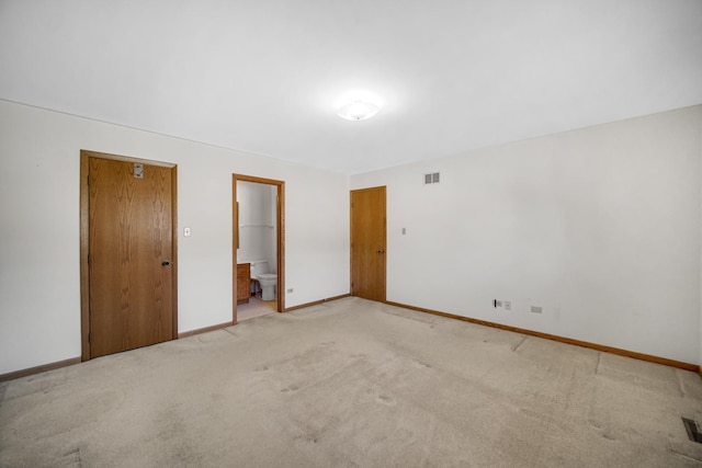 unfurnished bedroom featuring connected bathroom, light colored carpet, and a closet