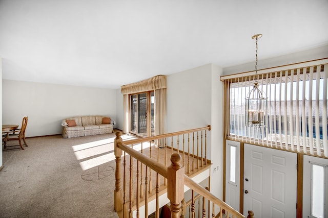 hall with carpet flooring, an inviting chandelier, and a wealth of natural light