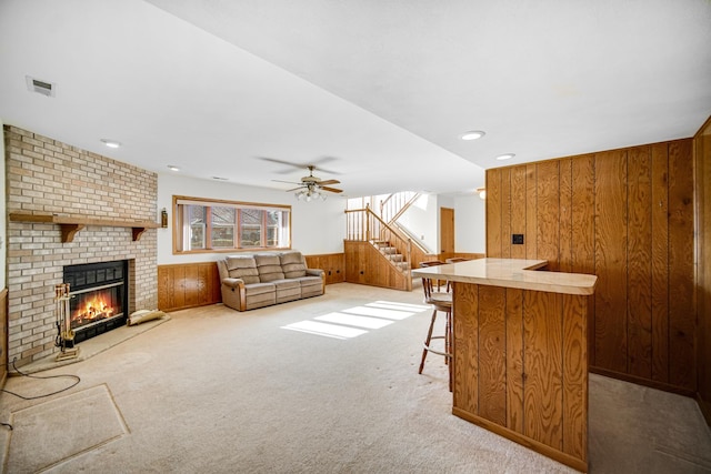 bar featuring carpet, a brick fireplace, ceiling fan, and wood walls