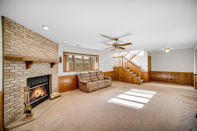 carpeted living room featuring wooden walls, ceiling fan, and a brick fireplace