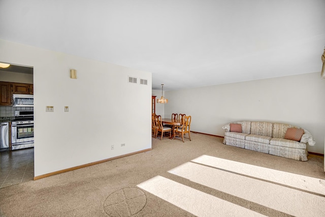 carpeted living room with a notable chandelier