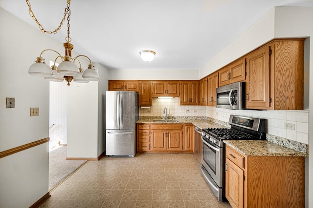 kitchen with backsplash, sink, appliances with stainless steel finishes, a notable chandelier, and light stone counters