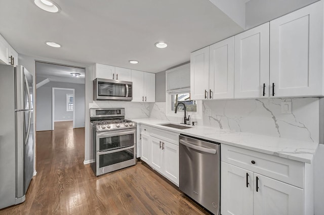 kitchen featuring backsplash, stainless steel appliances, white cabinetry, and sink