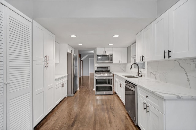 kitchen with decorative backsplash, stainless steel appliances, white cabinets, and sink