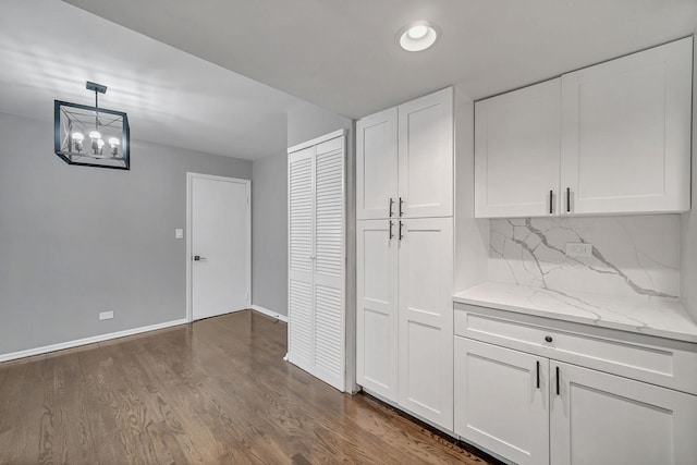 bar featuring an inviting chandelier, white cabinets, decorative backsplash, decorative light fixtures, and light stone counters