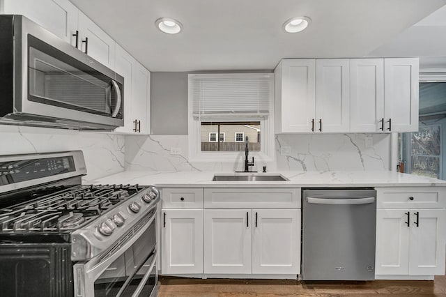 kitchen featuring backsplash, white cabinets, sink, appliances with stainless steel finishes, and light stone counters