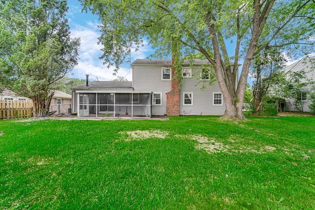 rear view of property featuring a lawn and a sunroom